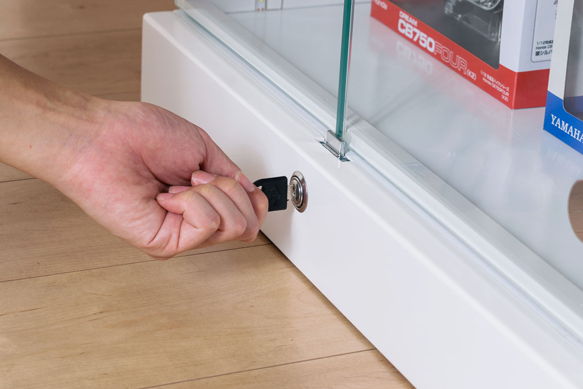 鍵付きのガラスコレクションケースで推しグッズを守るイメージ